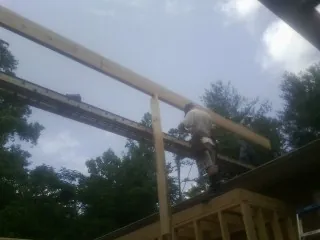 Carpenter setting a ridge beam over a new addition frame — Ice Dam Removal by Roofing Brothers in Augusta Springs