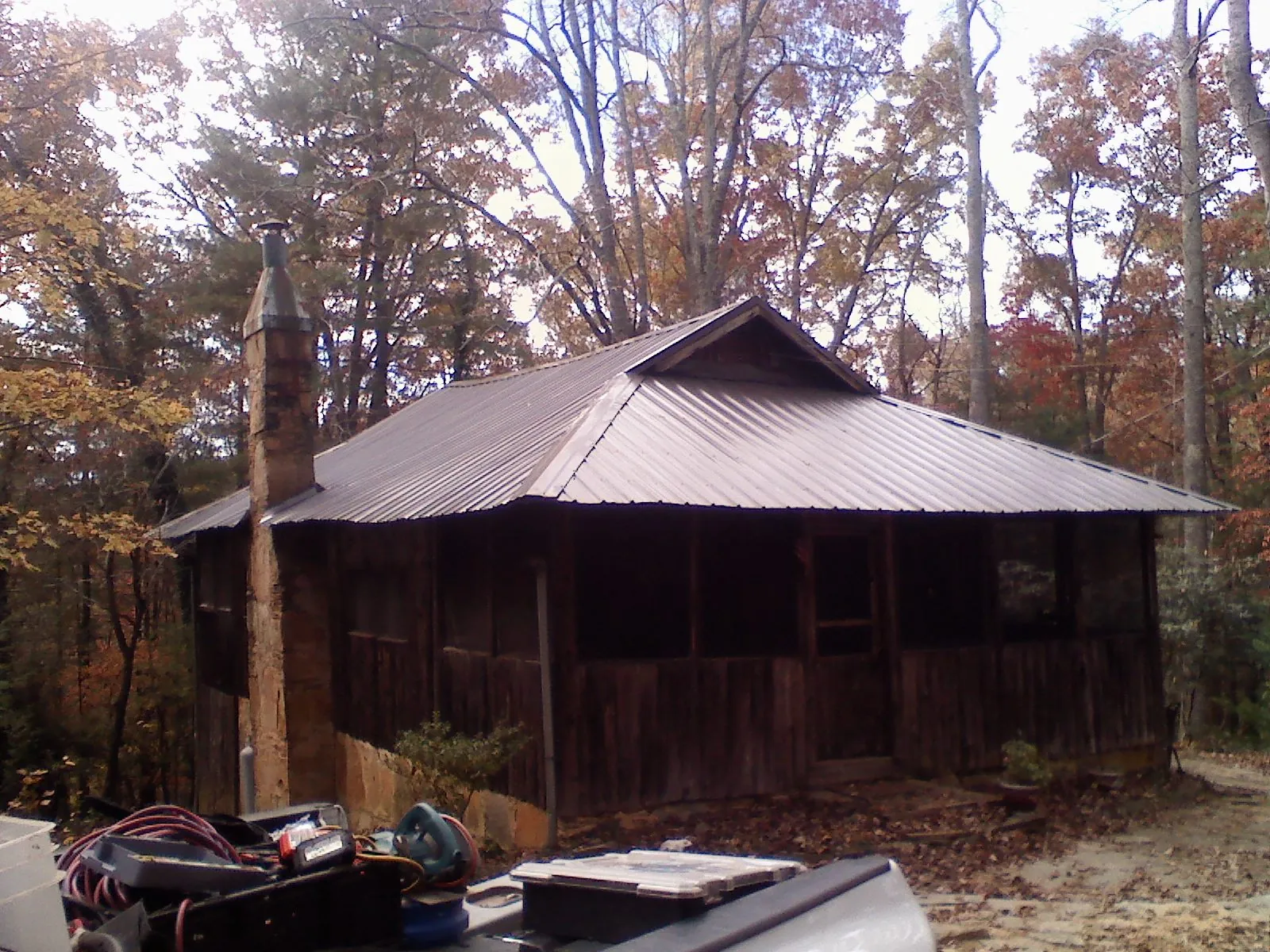 Brown metal hip roof on an old cabin with a stone chimney in Augusta Springs