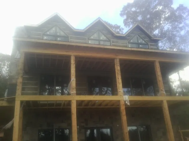 Dormers and porch framing on a large log home under construction — Roof Coating work by our crew in Augusta Springs