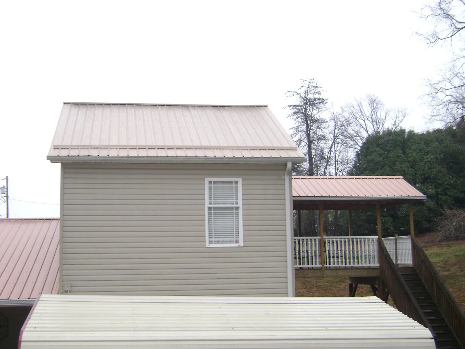 Tan metal roofs on a two story addition and attached porch, from a Roof Replacement job in Augusta Springs