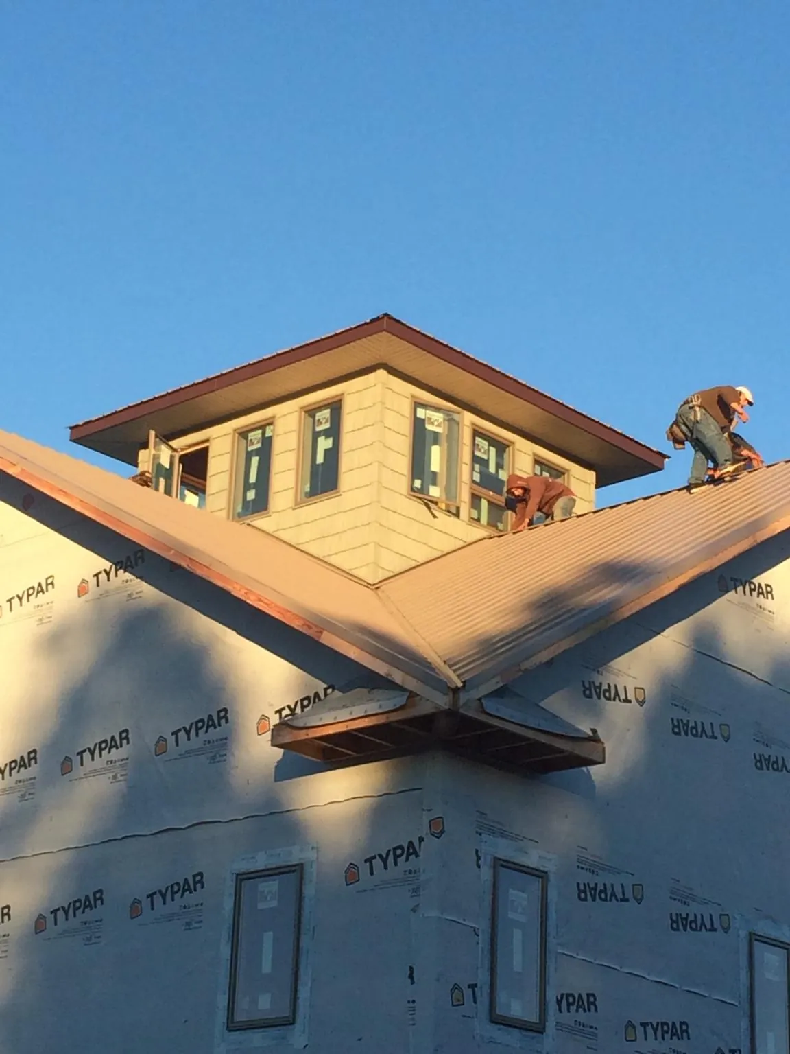 Roofers working around a rooftop cupola on a new metal roof at sunset — Roof Waterproofing in Augusta Springs by Roofing Brothers